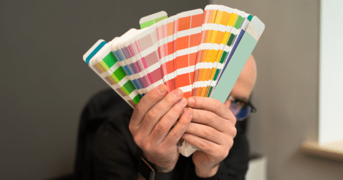 A Pantone color bridge guide being held by a designer and spread open in the shape of a fan.